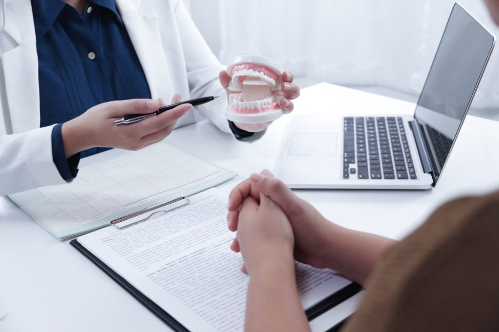 a dentist explaining treatment process to a patient using a dental model