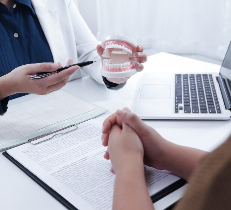 a dentist explaining treatment process to a patient using a dental model