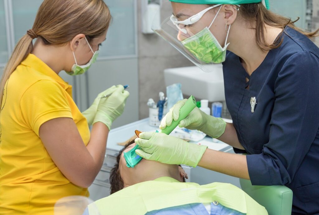 a dentist and her assistant examining a patient’s teeth in a dental clinic