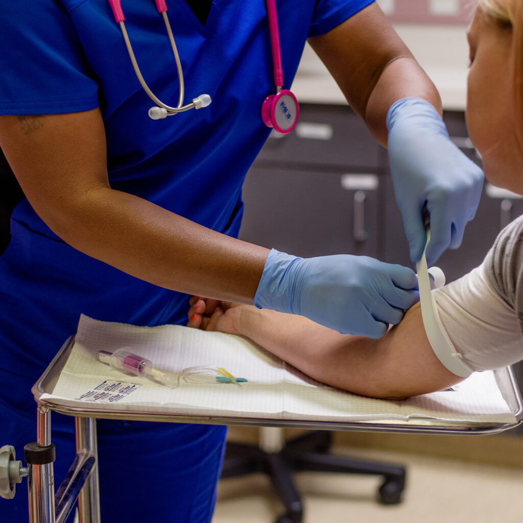 medical assistant putting a tourniquet around a patient's arm