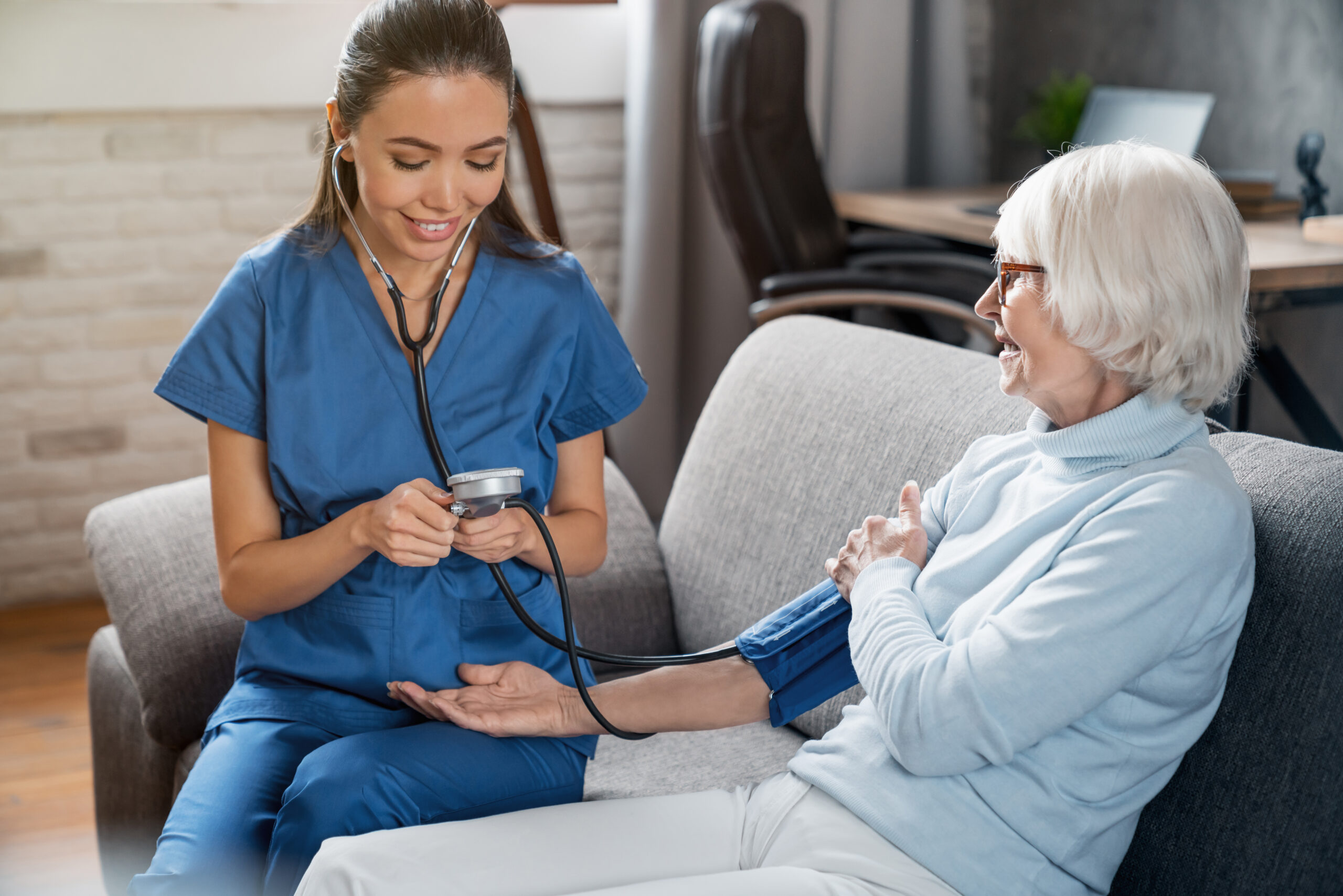 a certified nursing assistant checking the blood pressure of a senior woman