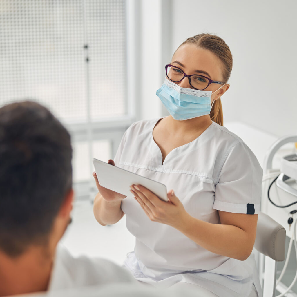 female esthetician with tablet computer talking with male patient