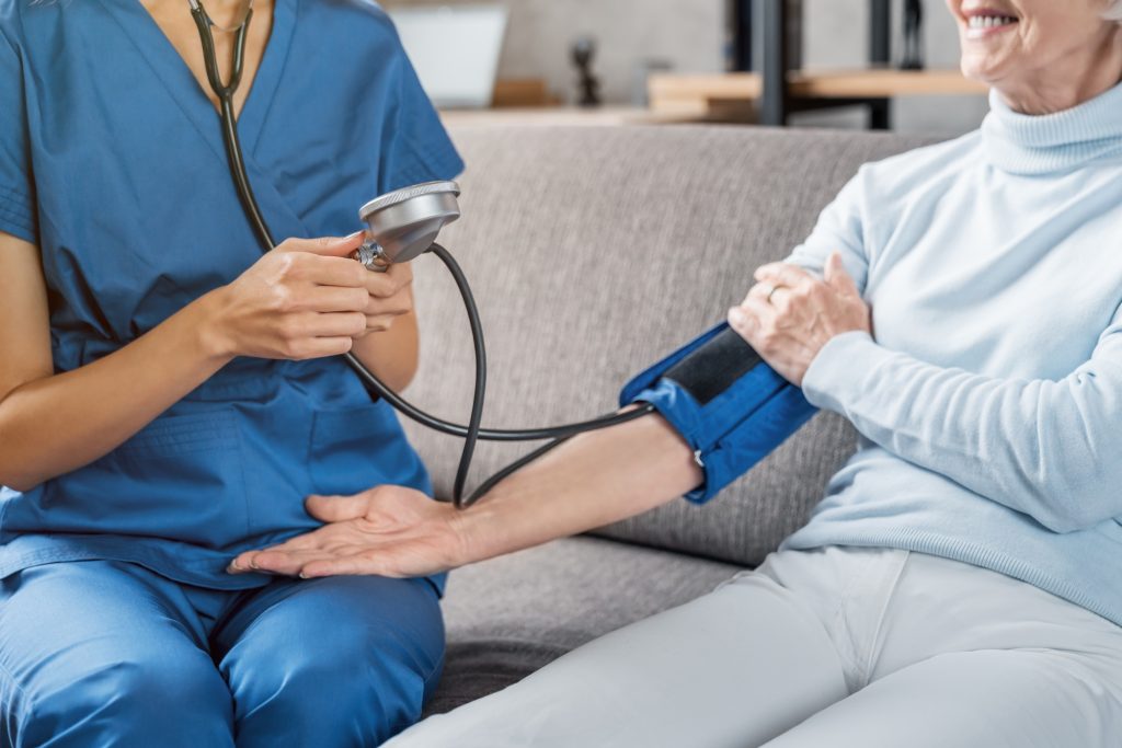 medical assistant measuring female patient blood pressure