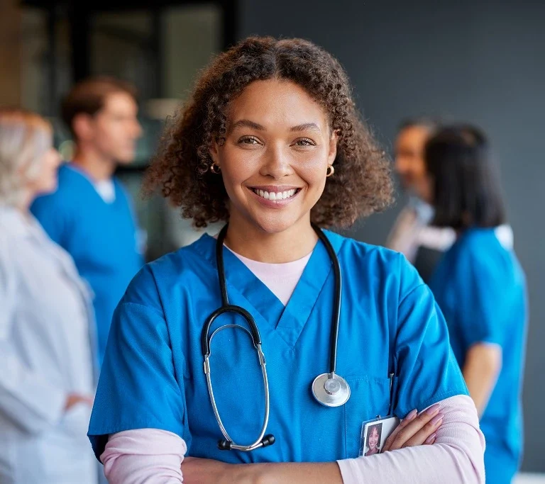 female nurse in blue scrubs smiling confidently, showcasing detail-oriented skills
