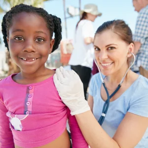 volunteer nurse examines young girl during community outreach, highlighting volunteer work on resume