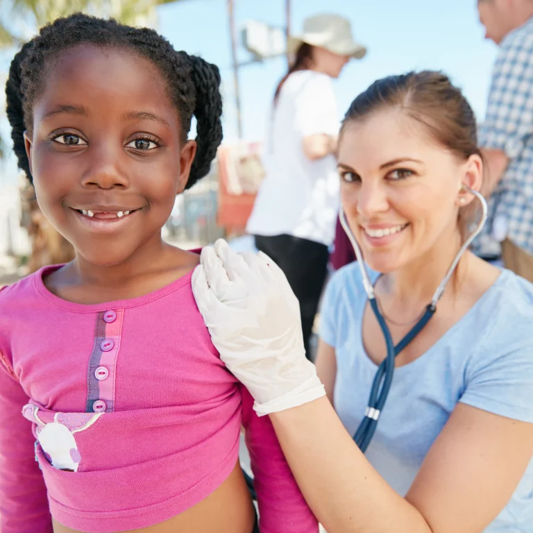 volunteer nurse examines young girl during community outreach, highlighting volunteer work on resume