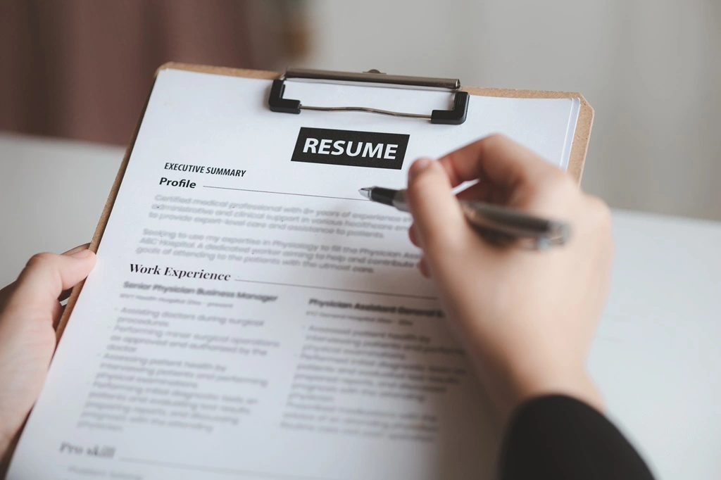 medical professional writing down key skills for doctor resume on a notepad
