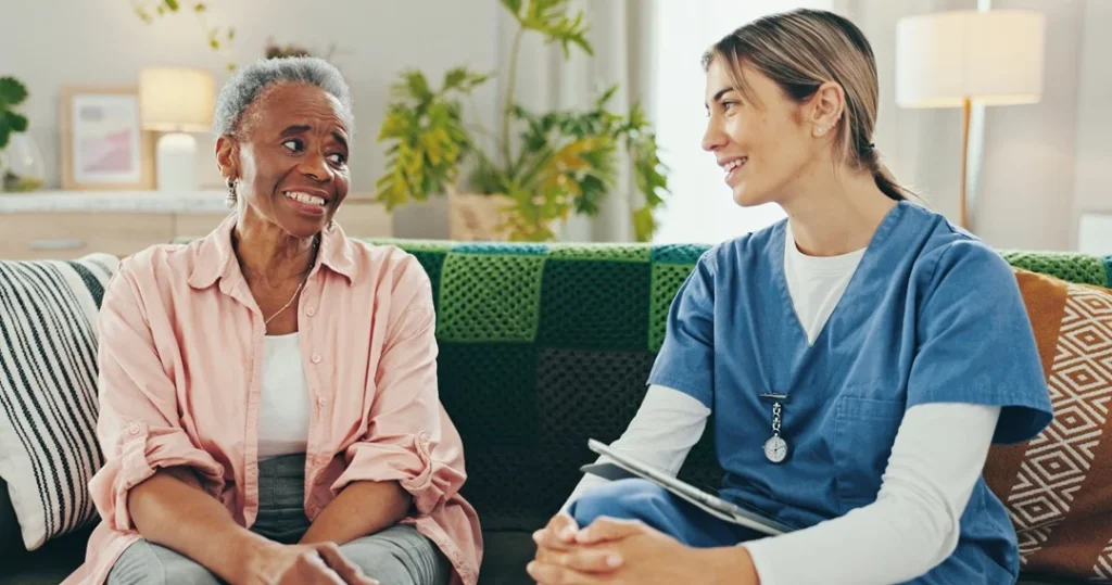 senior woman chatting with young Home Health Aide